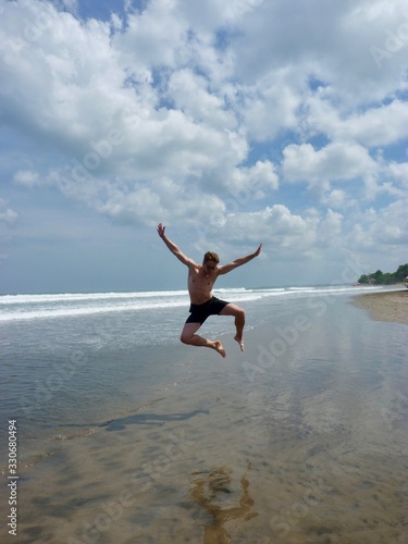 Athletic man jumping into the air on beach, Bali, Indonesia