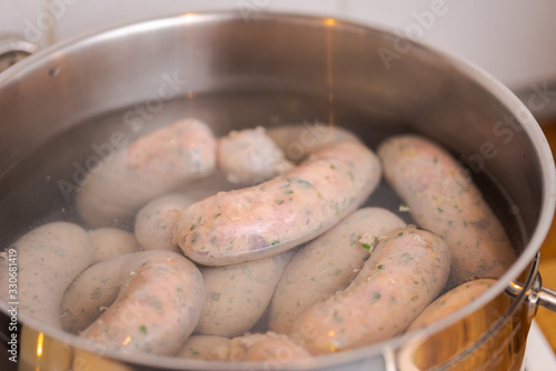 Making bavarian white sausages at home, chain of sausages  boiling in pot with hot water photo