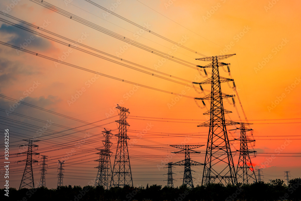 Fototapeta premium Przemysłowa wieża energii elektrycznej wysokiego napięcia i piękna przyroda o zachodzie słońca latem