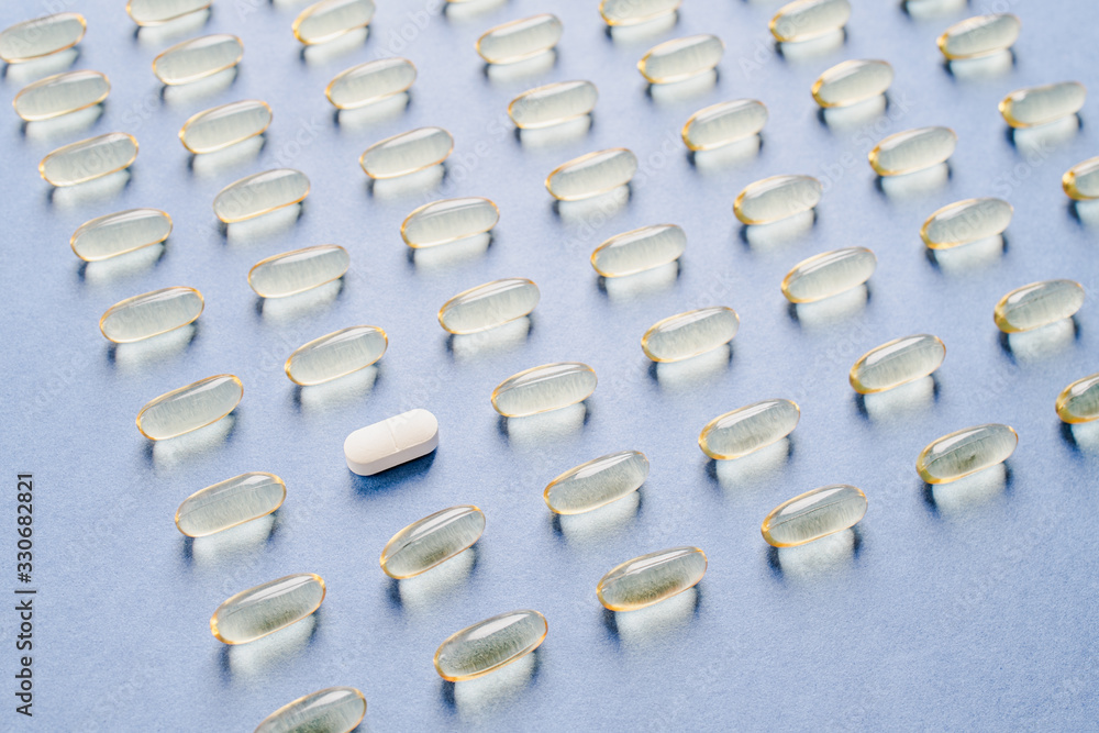 Obraz premium Yellow capsules with vitamin D on a blue background. Sunshine vitamin.