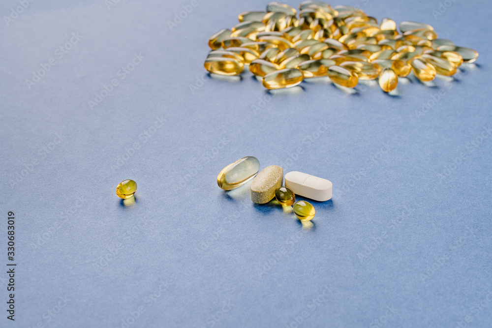 Yellow capsules with vitamin D on a blue background. Sunshine vitamin.