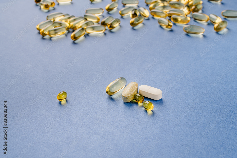 Yellow capsules with vitamin D on a blue background. Sunshine vitamin.