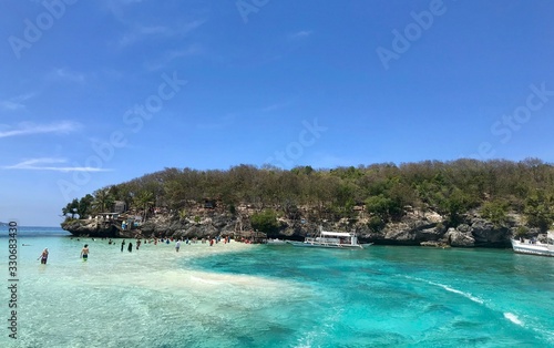 Scenic view over beach with boats and tourists, green and blue water, island in background, Cebu Island, Philippines © HWL Photos