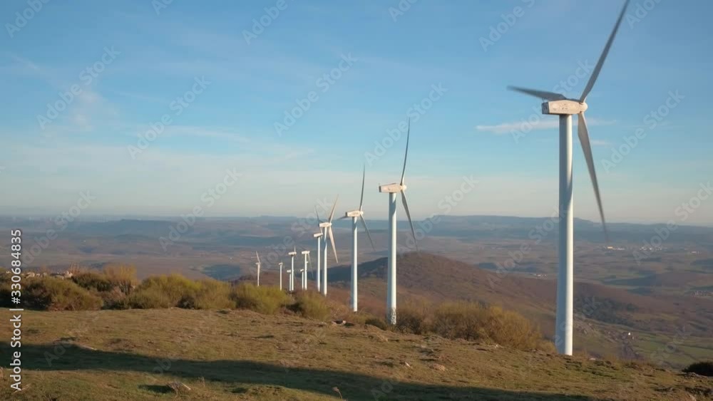Windmills aligned and rotating with sunset sunbathing blue sky Windmills aligned and rotating with sunset sunbathing blue sky