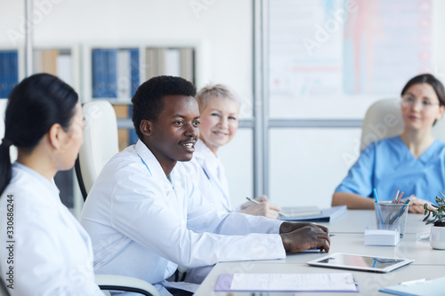 Portrait of young African-American doctor speaking during medical conference and smiling happily, copy space