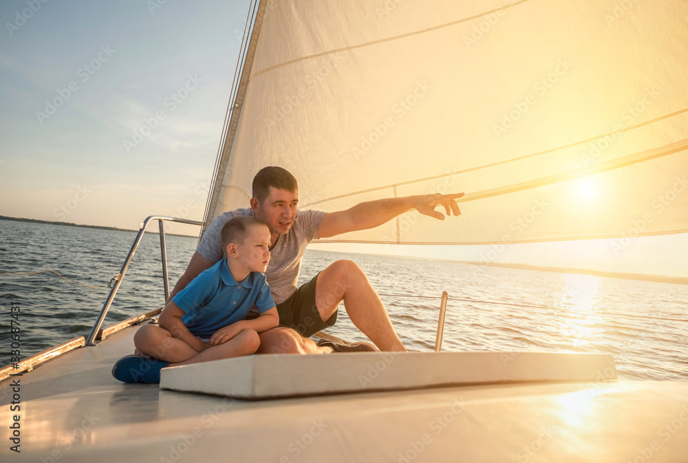 Happy traveler father and son enjoying sunset from deck of saili - obrazy, fototapety, plakaty 
