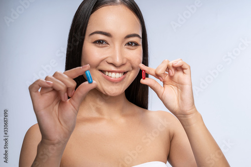 Happy pretty Asian woman posing with vitamins