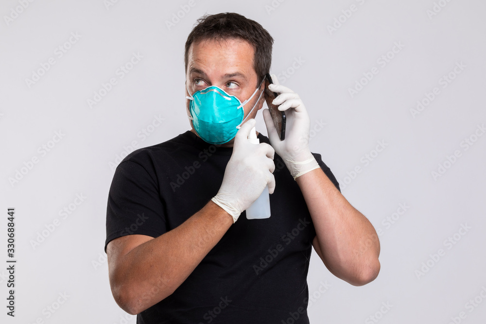 Fearful man disinfecting his phone while speaking to someone. Fearful man disinfecting his phone while speaking to someone.