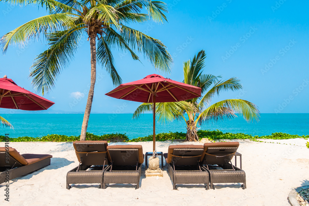 Beautiful tropical beach sea ocean with umbrella and chair around coconut palm tree on blue sky