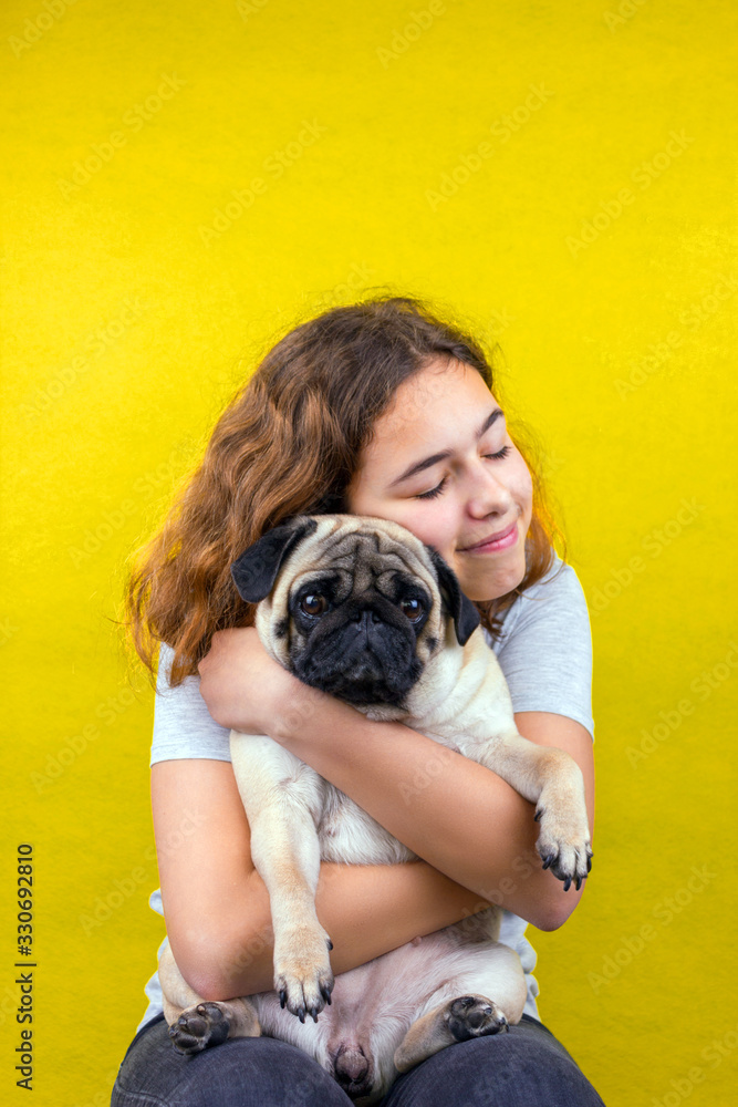 Pet love. Curly teenager girl hugs her sad pug dog with love Pet love. Curly teenager girl hugs her sad pug dog with love