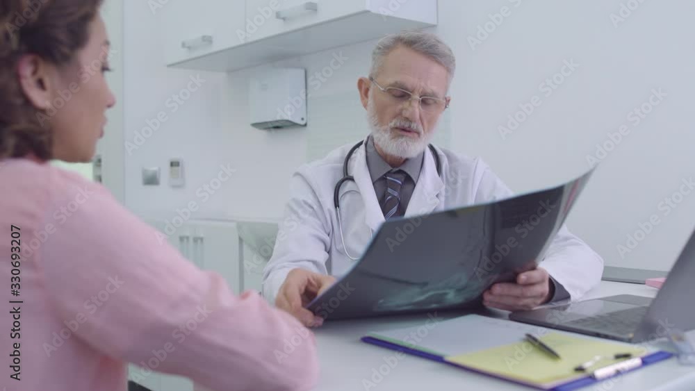 Surgeon looking at x-ray image, consultation with doctor in clinic, diagnostics Surgeon looking at x-ray image, consultation with doctor in clinic, diagnostics