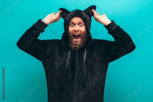 Cheerful bearded man in black cat kigurumi pajama. Crazy emotions. Pajamas party photo