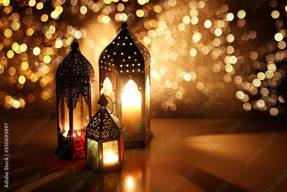 Foto Stock Ornamental Arabic lanterns with glittering bokeh lights. Burning  candles on table glowing at night. Festive greeting card, invitation for  Muslim holiday Ramadan Kareem. Golden Iftar background. | Adobe Stock