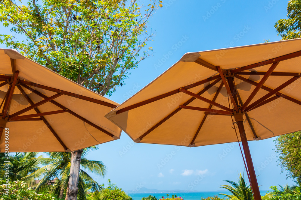 Umbrella and chair around sea beach ocean with coconut palm tree on blue sky background