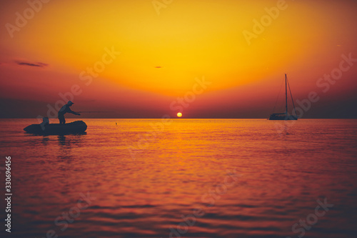 Silhouette of a fisherman fishing in sunset time on the open sea.