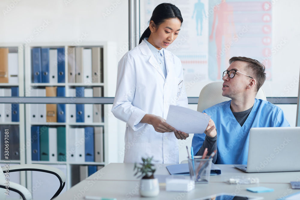 Portrait of young Asian doctor consulting supervisor during internship in clinic, copy space Portrait of young Asian doctor consulting supervisor during internship in clinic, copy space
