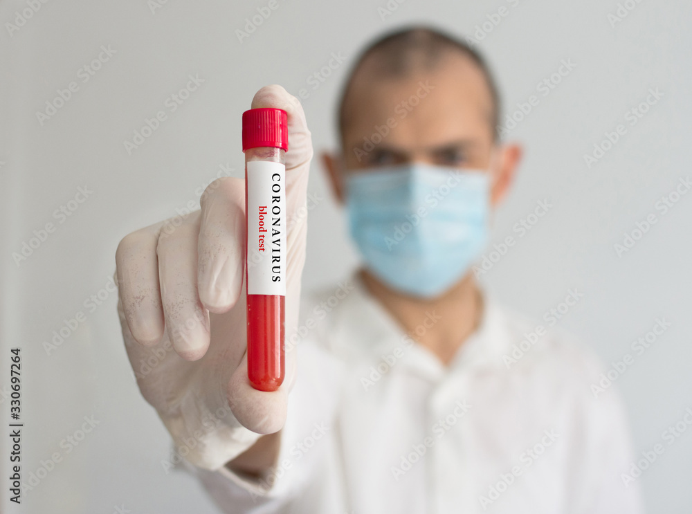 Doctor wearing a medical face mask and gloves, holding a blood test result for the Coronavirus COVID-19 outbreak. Coronavirus blood test conceptual photo. Doctor wearing a medical face mask and gloves, holding a blood test result for the Coronavirus COVID-19 outbreak. Coronavirus blood test conceptual photo.