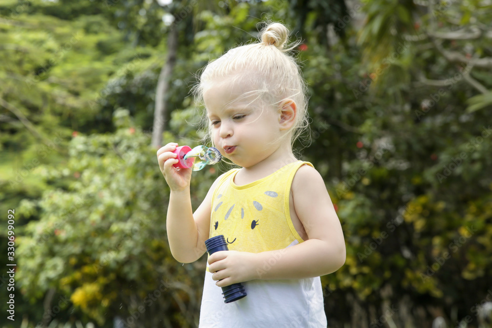 Happy little toddler girl blowing soap bubbles in the park Happy little toddler girl blowing soap bubbles in the park