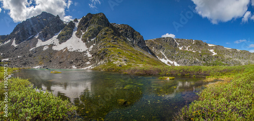 Mountain lake, snow on the slopes, rocky peaks. Traveling in the mountains, trekking. © Valerii