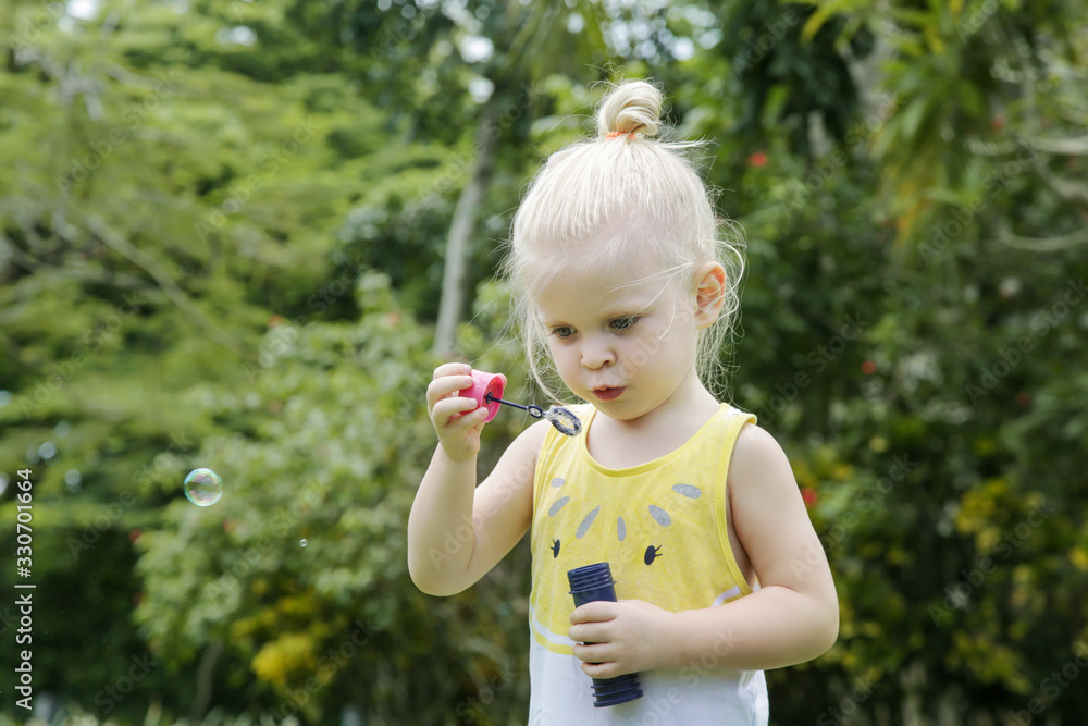 Happy little toddler girl blowing soap bubbles in the park Happy little toddler girl blowing soap bubbles in the park