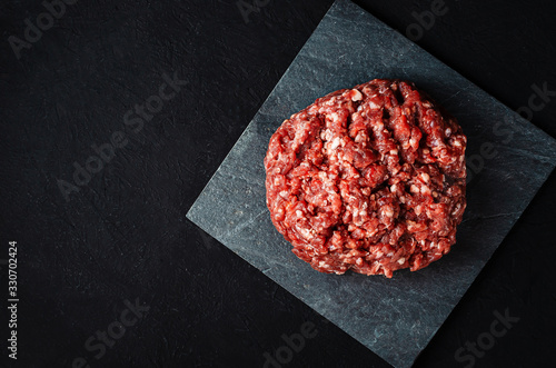 pile of fresh raw minced meat for cutlets on a black background.