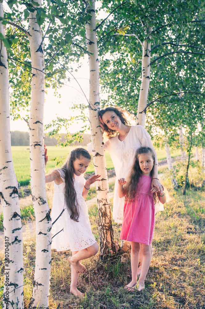 Fototapeta premium A family of three girls among the birches in the field