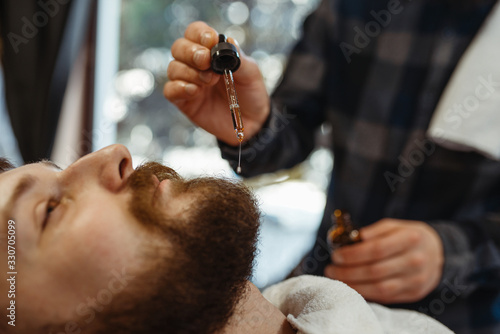 Barber and customer, beard cutting closeup