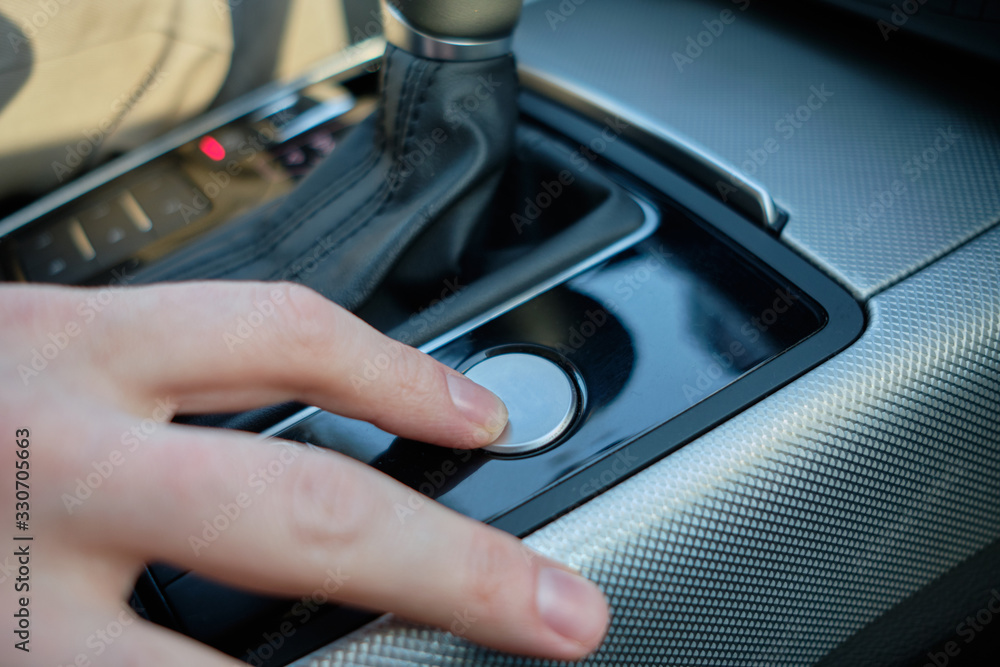 A man in a modern car. Hand turns on the ignition.