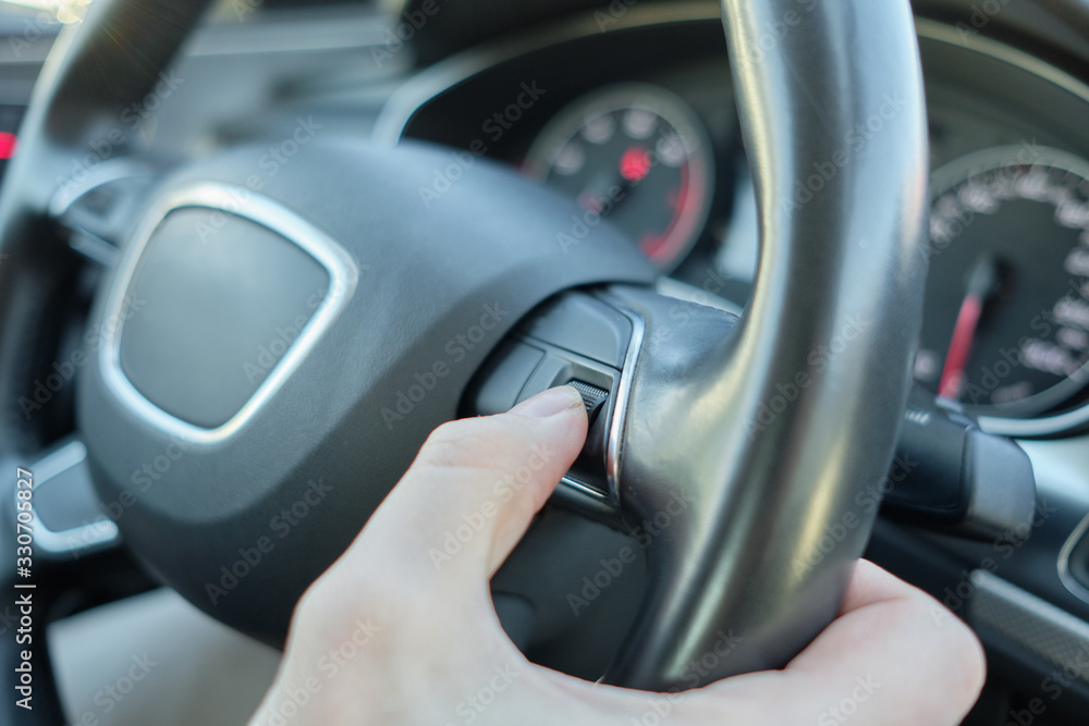 A man in a modern car. Turns a hand with a disk with a volume level of music.