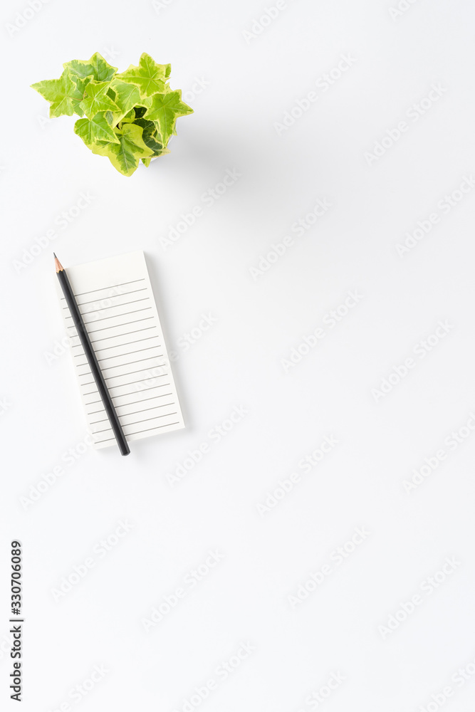 Elegant office desktop with notebook, pencil and flower on white background with copyspace. Business background. Top view Elegant office desktop with notebook, pencil and flower on white background with copyspace. Business background. Top view