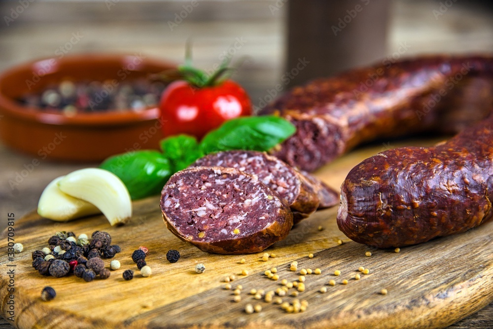 Smoked salami homemade with spices on a rustic wooden background Smoked salami homemade with spices on a rustic wooden background