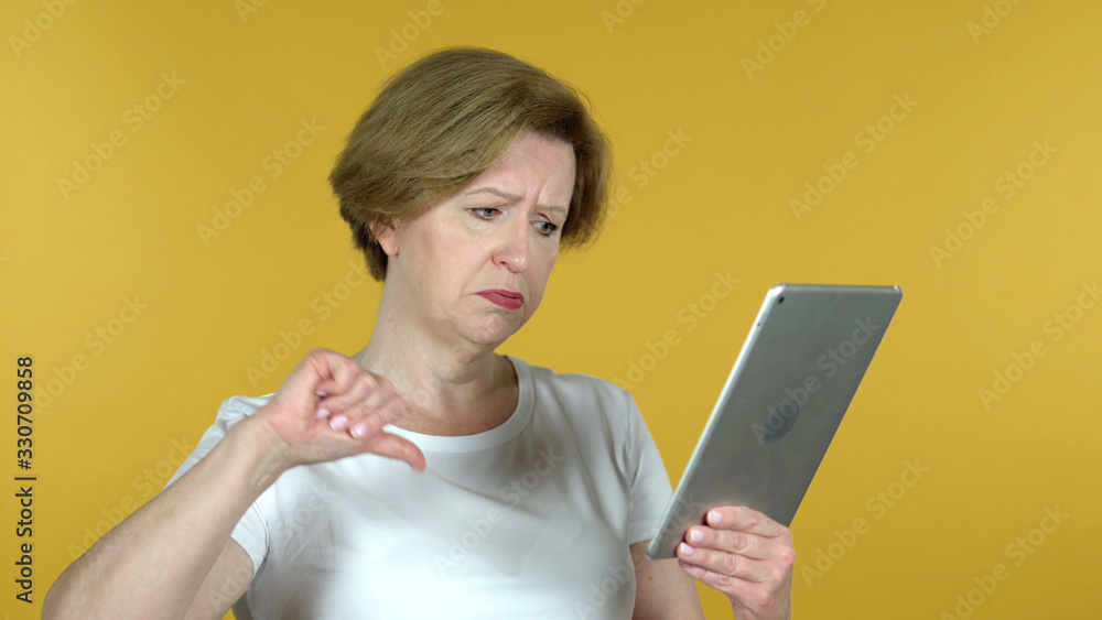 The Old Woman Reacting to Loss on Tablet Isolated on Yellow Background The Old Woman Reacting to Loss on Tablet Isolated on Yellow Background