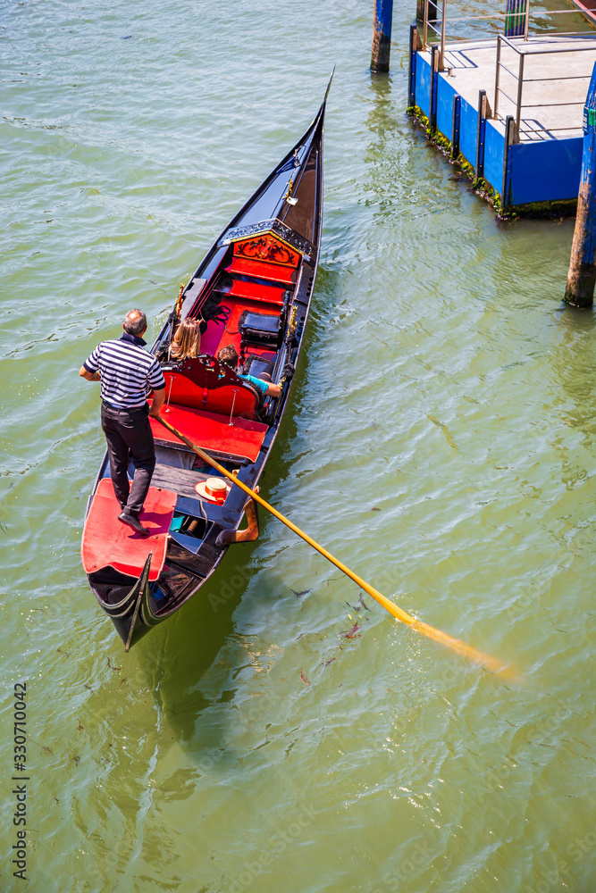 Gondolier carrying tourists on his Gondola in Venice Italy