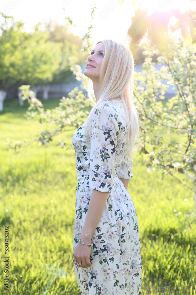 vertical portrait of a beautiful blonde in a long dress on a garden background vertical portrait of a beautiful blonde in a long dress on a garden background