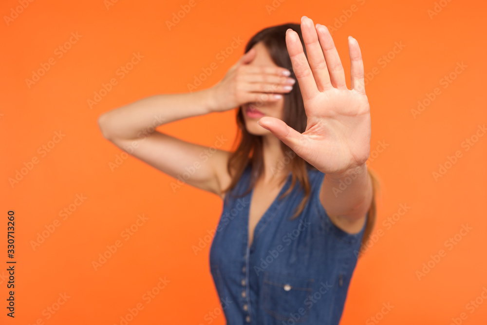 No, I won't look. Young brunette woman in denim dress covering eyes ...