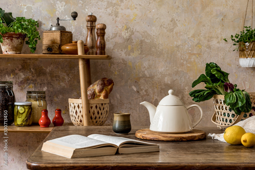 Stylish composition of kitchen interior with family table, vegetables, tea pot, dessert, shelf with food supplies, plants and kitchen accessories in wabi sabi concept of home decor. Stylish composition of kitchen interior with family table, vegetables, tea pot, dessert, shelf with food supplies, plants and kitchen accessories in wabi sabi concept of home decor.