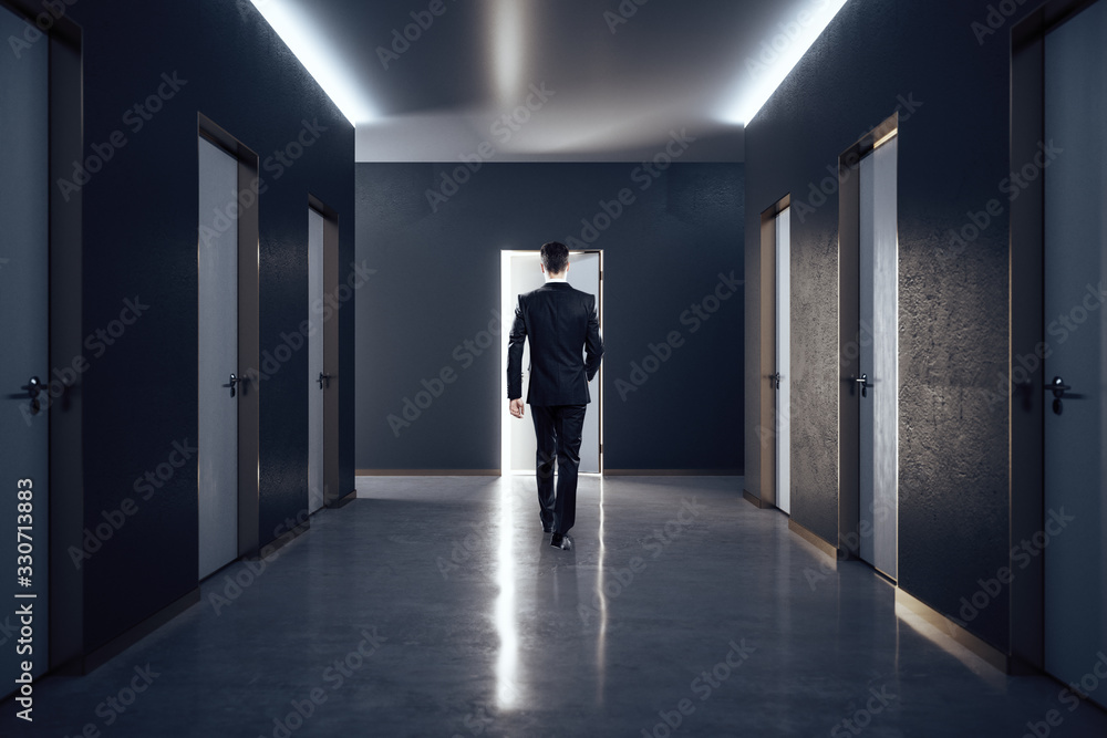 Businessman in hall interior with closed doors.