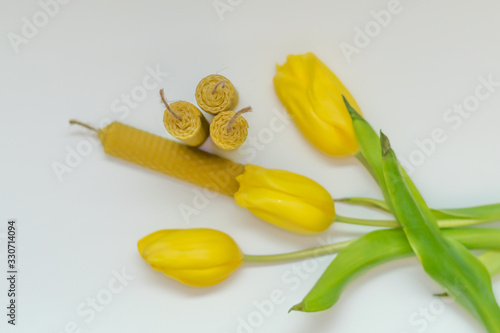 Wax candle and flowers. Magic, witchcraft background. Halloween rolled the candle. Handmade beeswax. Yellow tulips and craft wrapping aged paper. Environmental friendliness. eco friendly