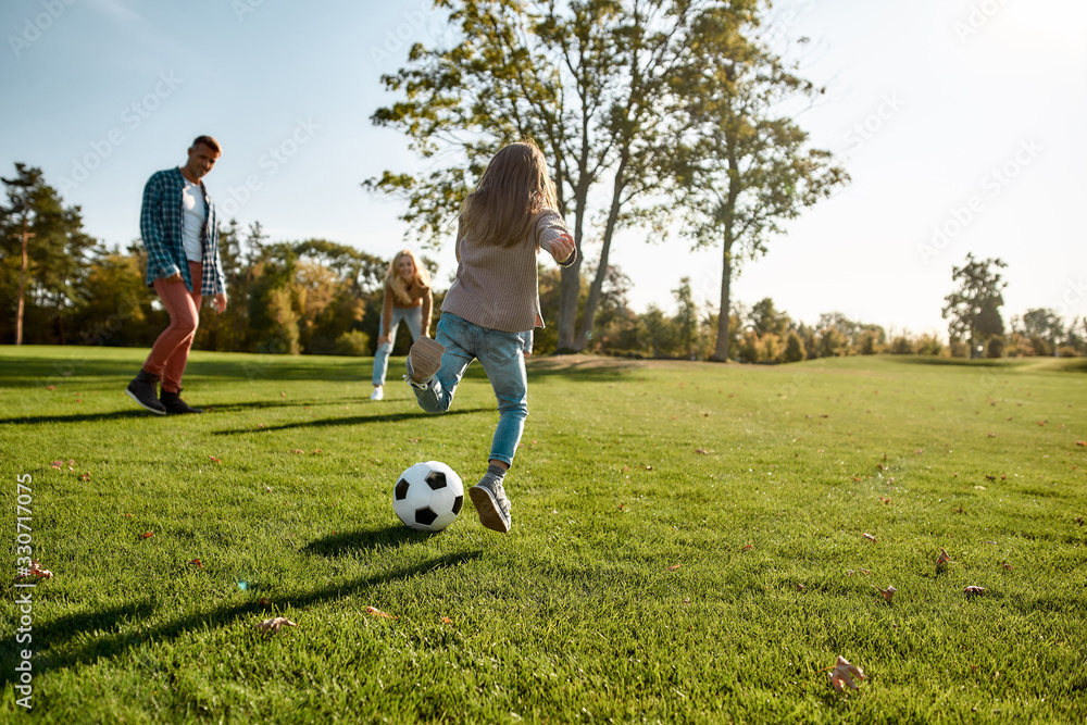 Obraz premium Brings the family together. Happy family playing with a ball on meadow