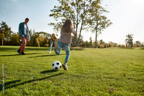 Brings the family together. Happy family playing with a ball on meadow