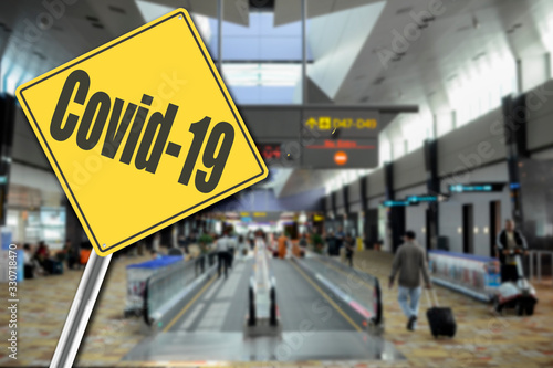 Passenger at airport with Covid-19 Sign
