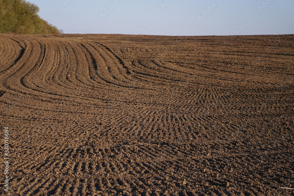 Plowed endless farm field. The fertile land of the agricultural sector. Sowing on black soil in the garden. Industrial stock theme Plowed endless farm field. The fertile land of the agricultural sector. Sowing on black soil in the garden. Industrial stock theme