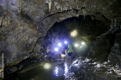 People in Cantabon cave with flash lights, standing water, Siquijor, Philippines