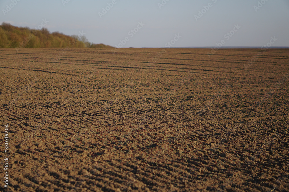 Plowed endless farm field. The fertile land of the agricultural sector. Sowing on black soil in the garden. Industrial stock theme
