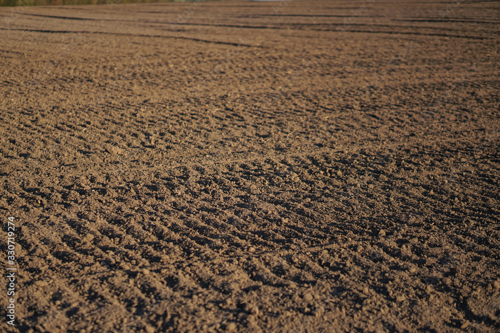 Plowed endless farm field. The fertile land of the agricultural sector. Sowing on black soil in the garden. Industrial stock theme Plowed endless farm field. The fertile land of the agricultural sector. Sowing on black soil in the garden. Industrial stock theme