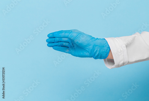 Doctor's hand in a blue medical glove holds an object on a blue background. infection control. mocap, you can insert your product for advertising © Nana_studio