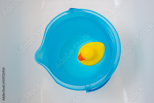 Yellow rubber duck in a blue bucket full of water 