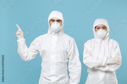 People in protective suits respirator masks isolated on blue background studio. Epidemic new rapidly spreading coronavirus 2019-ncov originating in Wuhan China virus concept pointing fingers copyspace