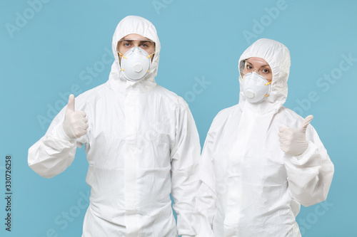 Two people in protective suits respirator masks isolated on blue background studio. Epidemic pandemic new rapidly spreading coronavirus 2019-ncov originating in Wuhan China, medicine flu virus concept