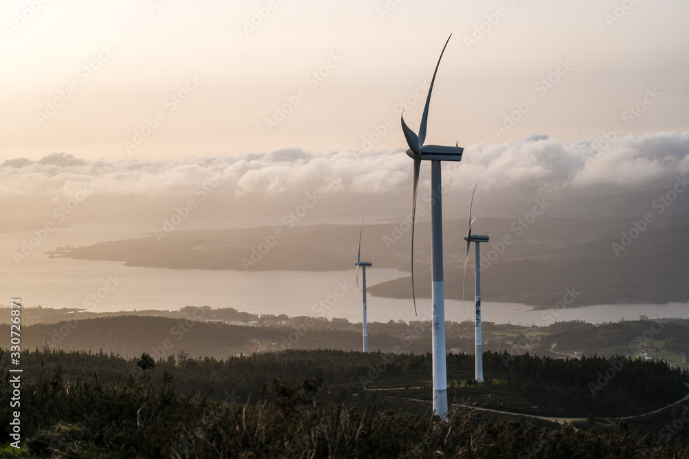 Obraz premium Beautiful view of field with wind turbines at sunset and cloudy sky in northern Spain